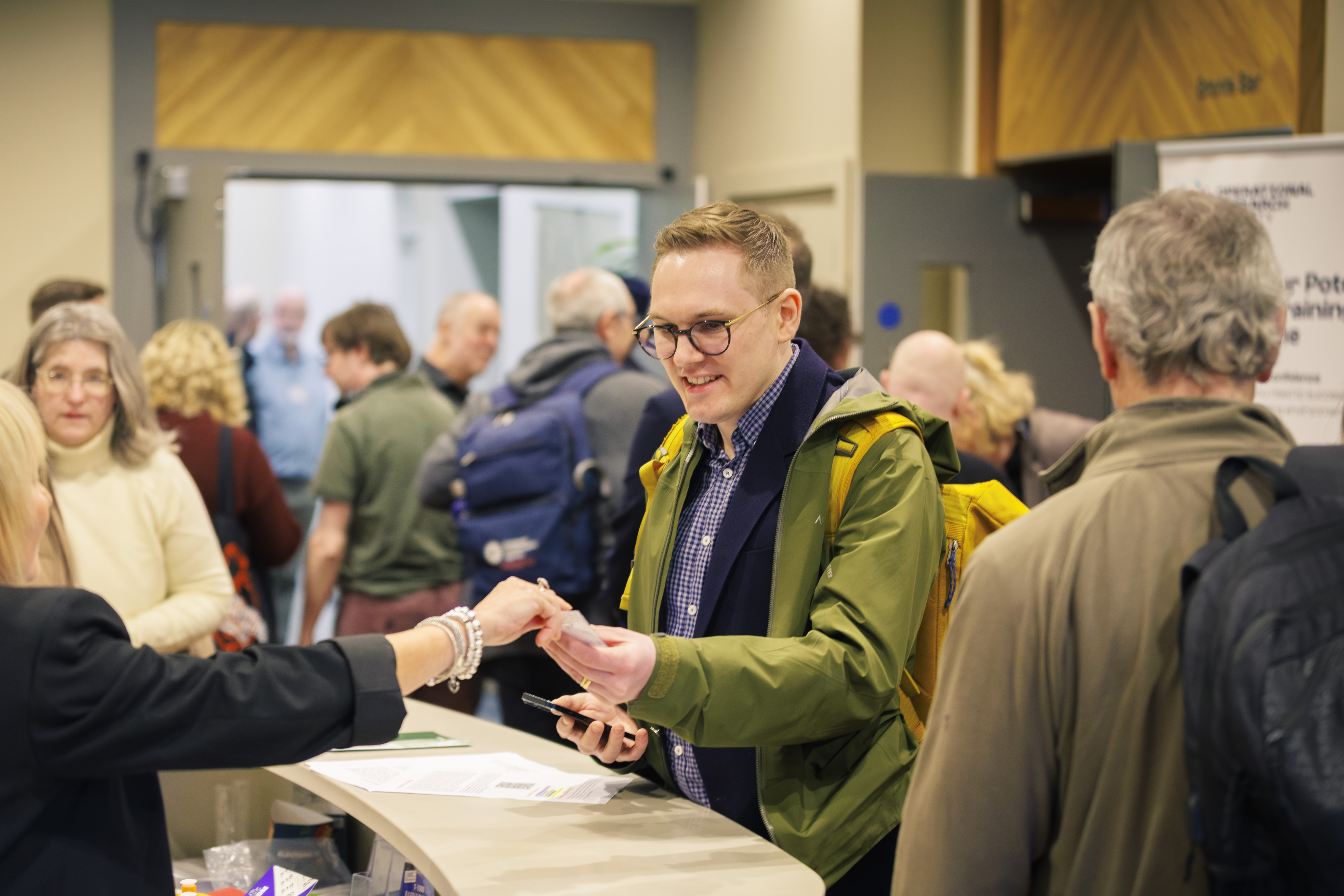 A man collects an accreditation badge from the reception desk a a conference