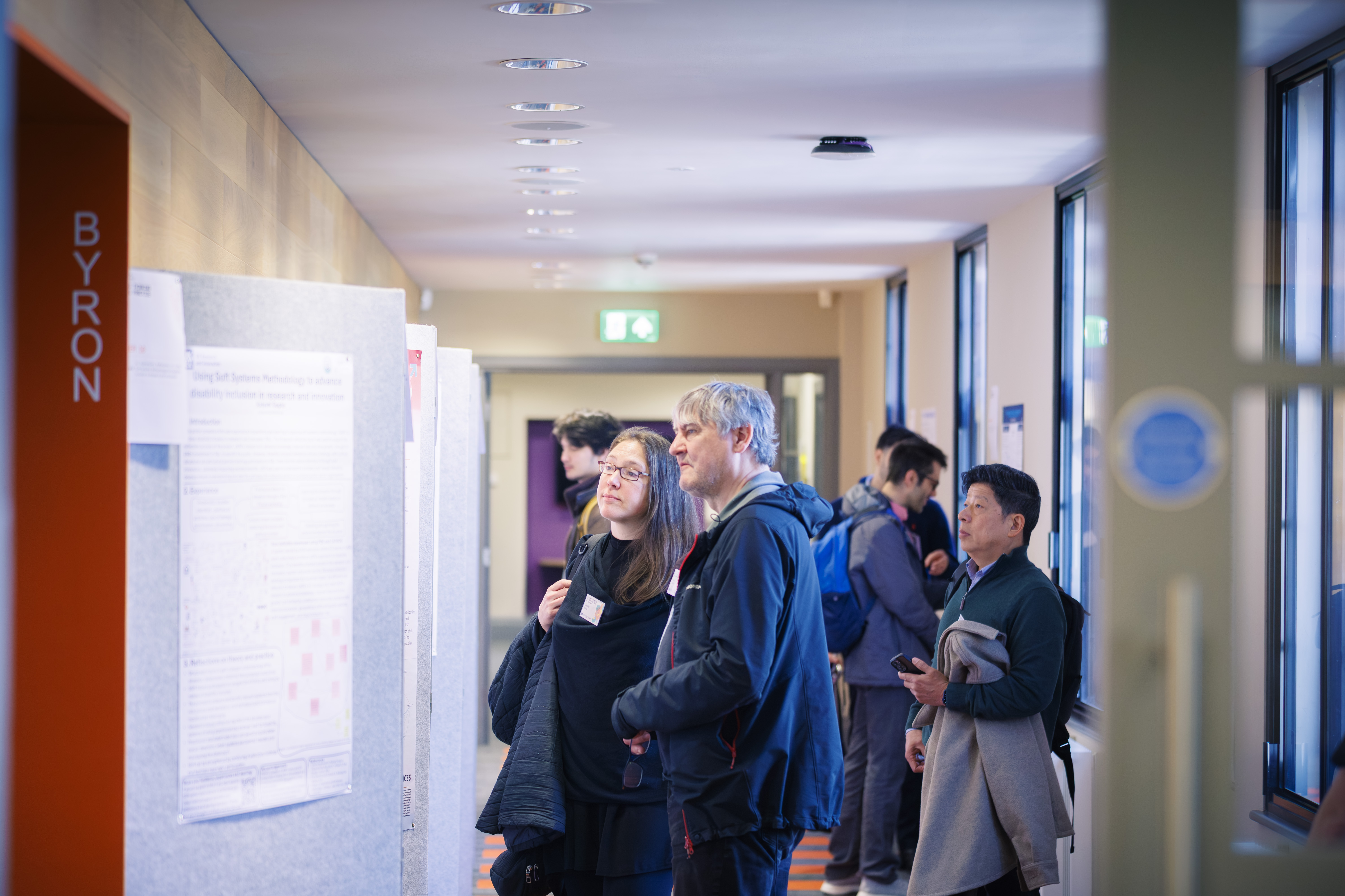 Several people examine posters on display in a corridor in Canham Turner