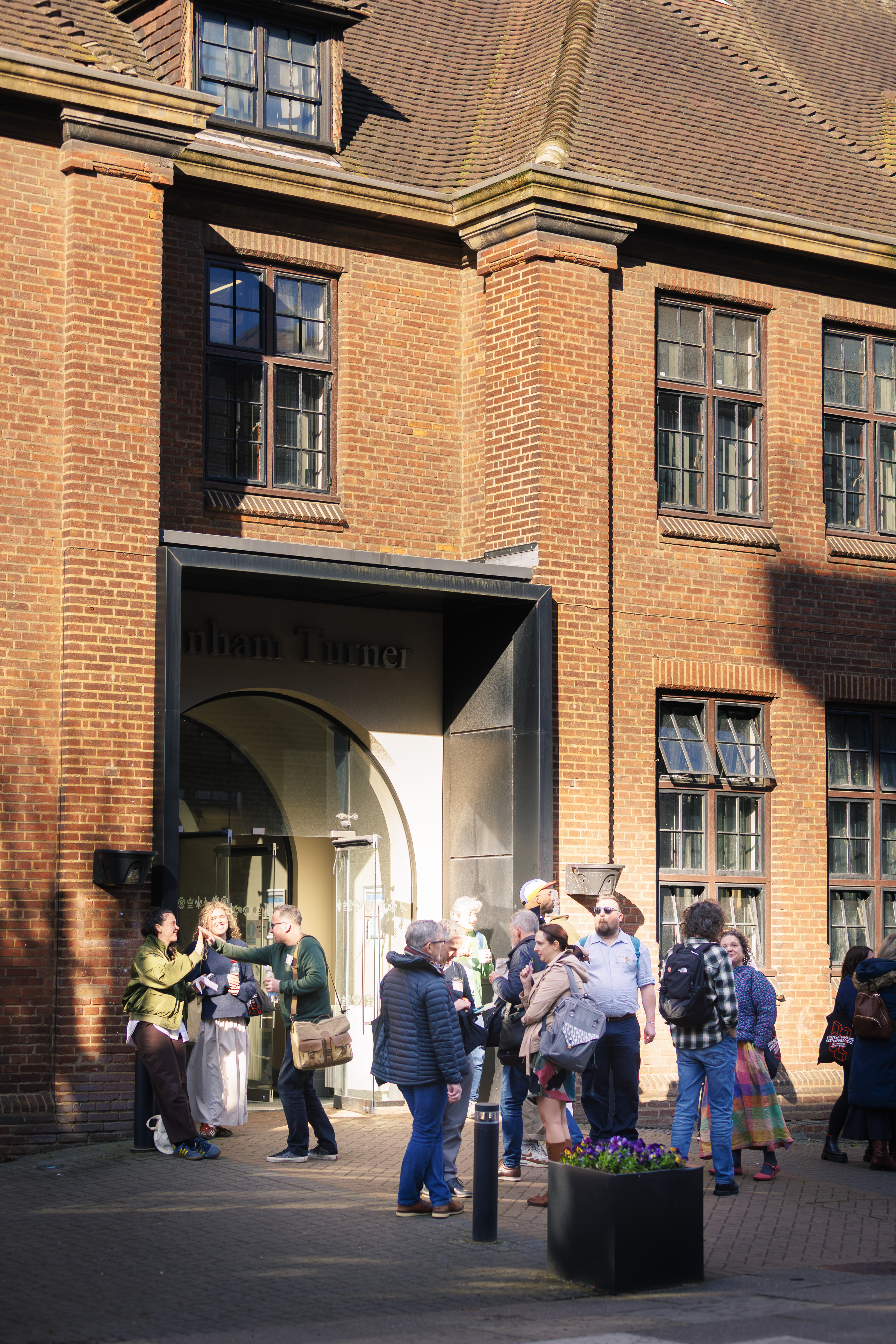 Conference attendees chat and network outside Canham Turner