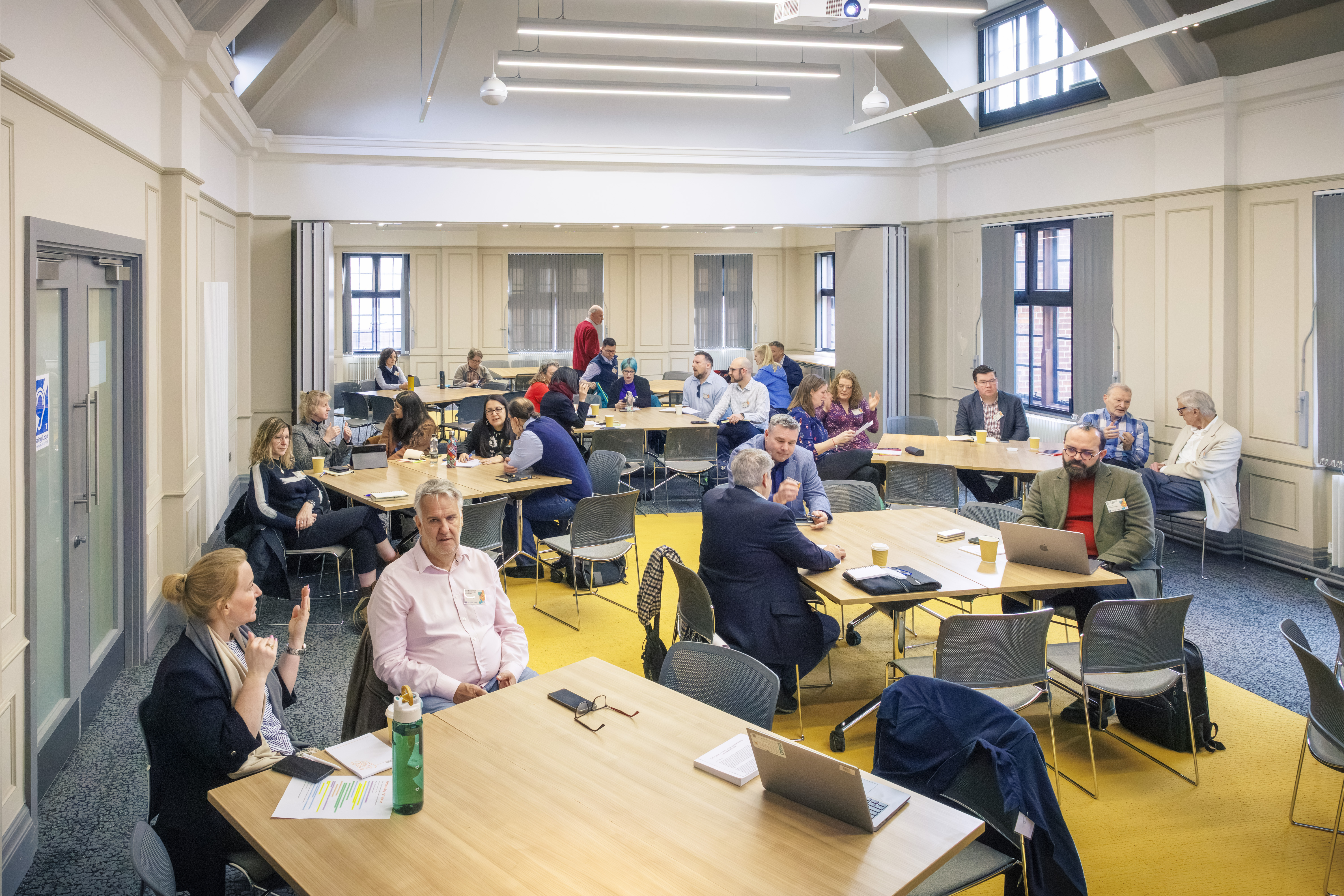 Groups of people in discussion around tables in a modern meeting space