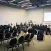 A handful of people watch a session in a large conference room that's been partitioned in half