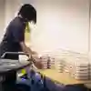 A worker delivers trays of food to a table at the back of a meeting room