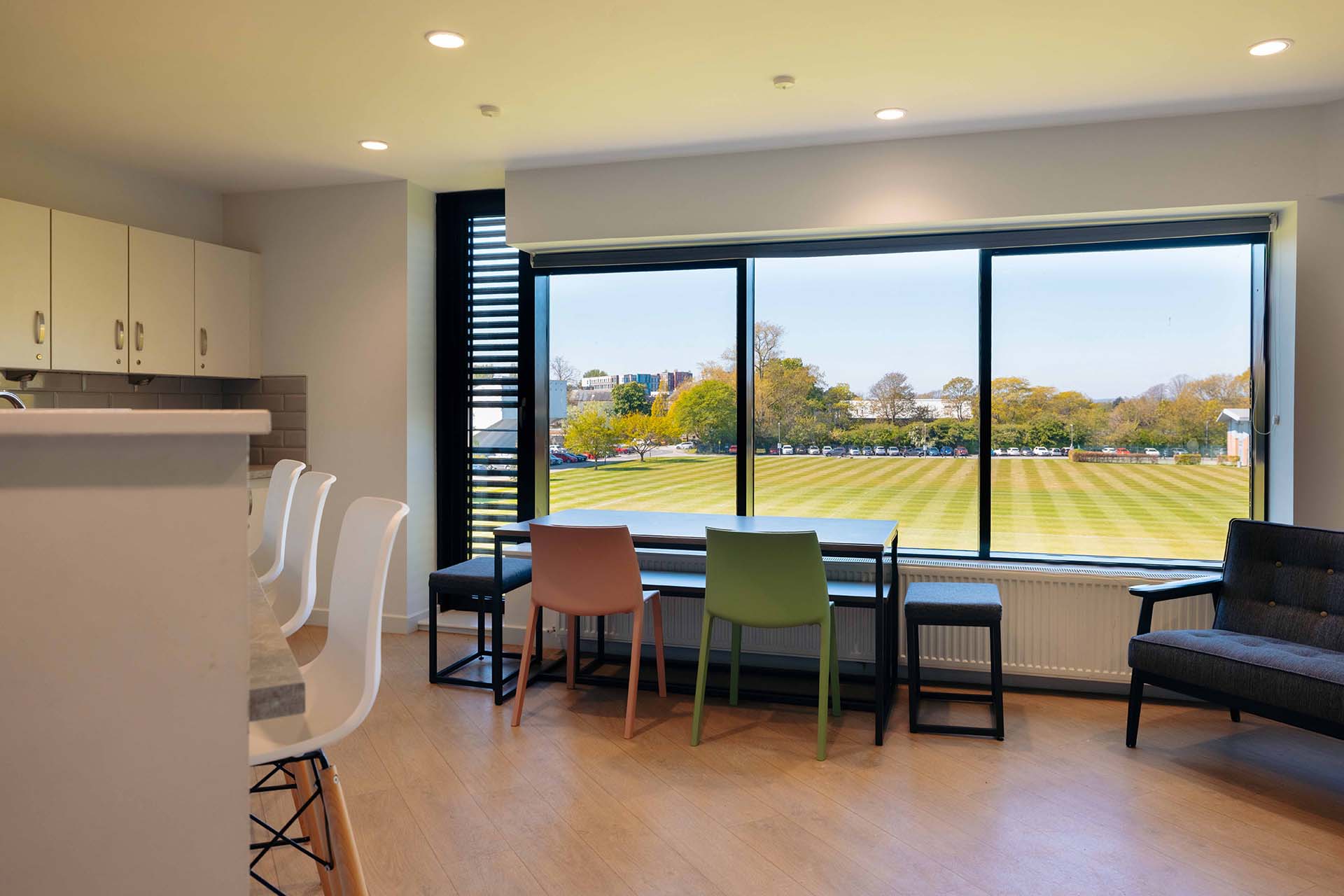 Table and chairs by a large kitchen window overlooking the playing field in The Courtyard.