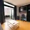 Spacious desk area in a rooftop flat at The Courtyard with balcony doors open to an outdoor patio space.