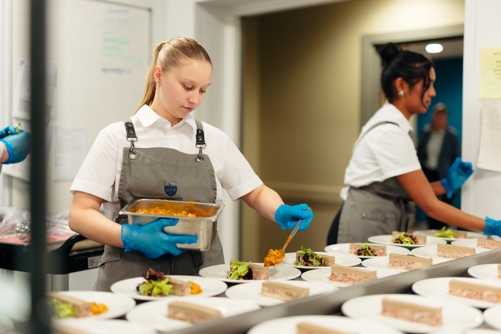 A female catering assistant plates up part of a meal