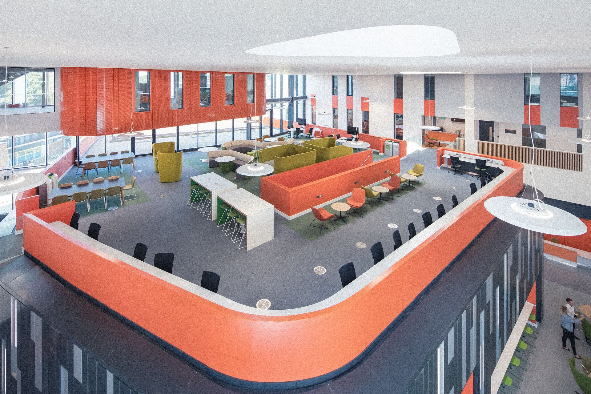 An aerial view of a large, open-plan breakout space in the Allam Medical Building with bright orange furntiure